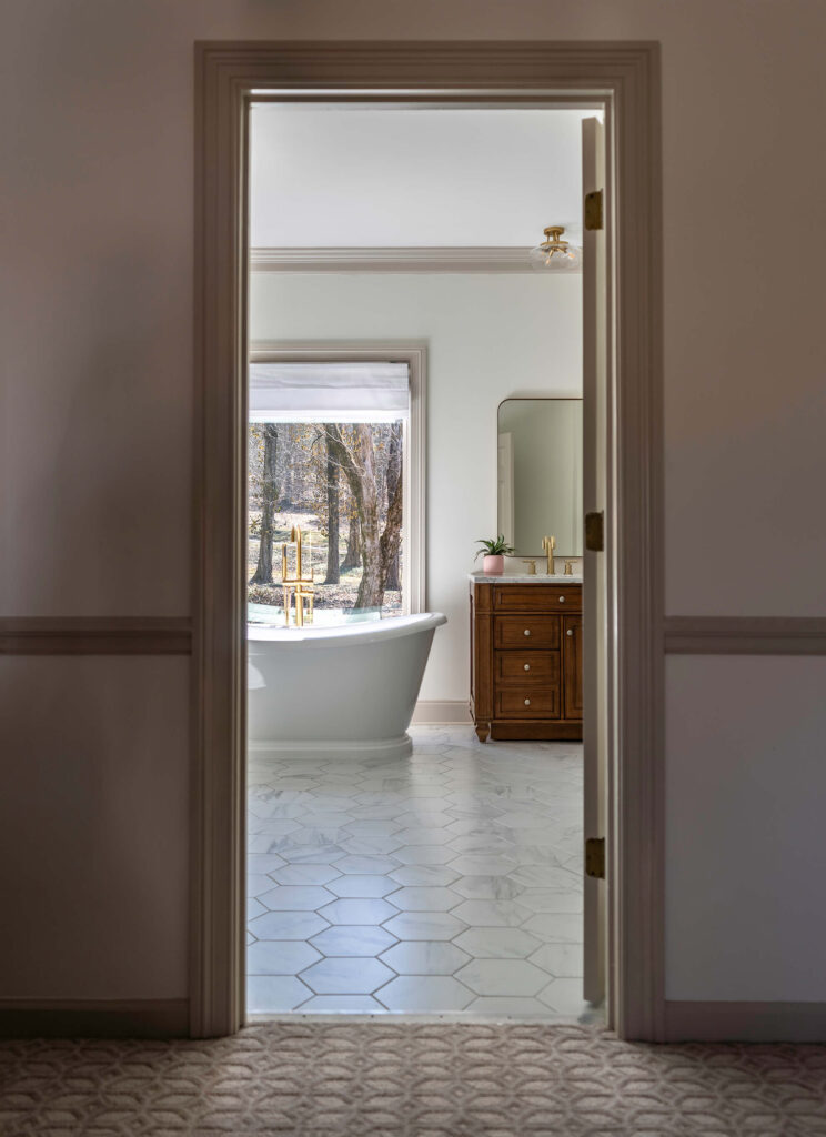 Patterned carpet in the hallway leading to the luxury home design bathroom with a freestanding bathtub visible.