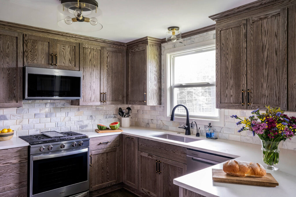 The guest cottage kitchen with dark wood cabinets going up to the ceiling, a white countertop, stainless steel appliances and modern flush lighting