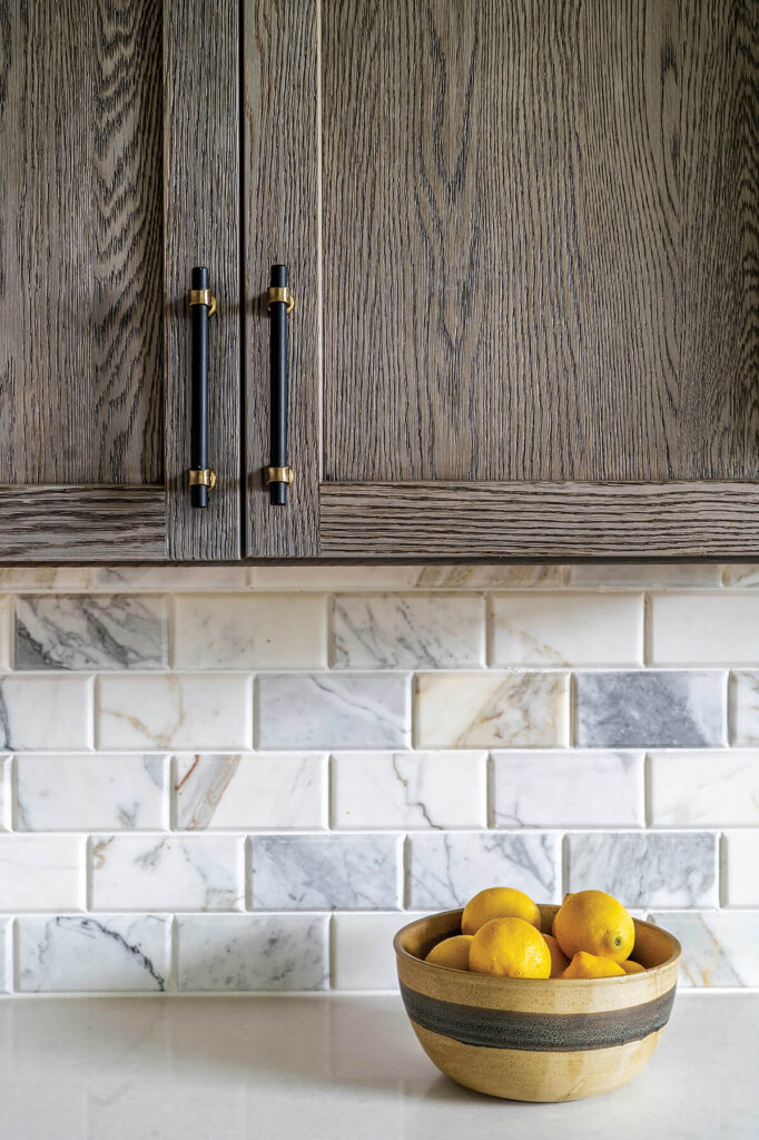 A close up of dark wood tone cabinets and a bowl of lemons sitting on the countertop