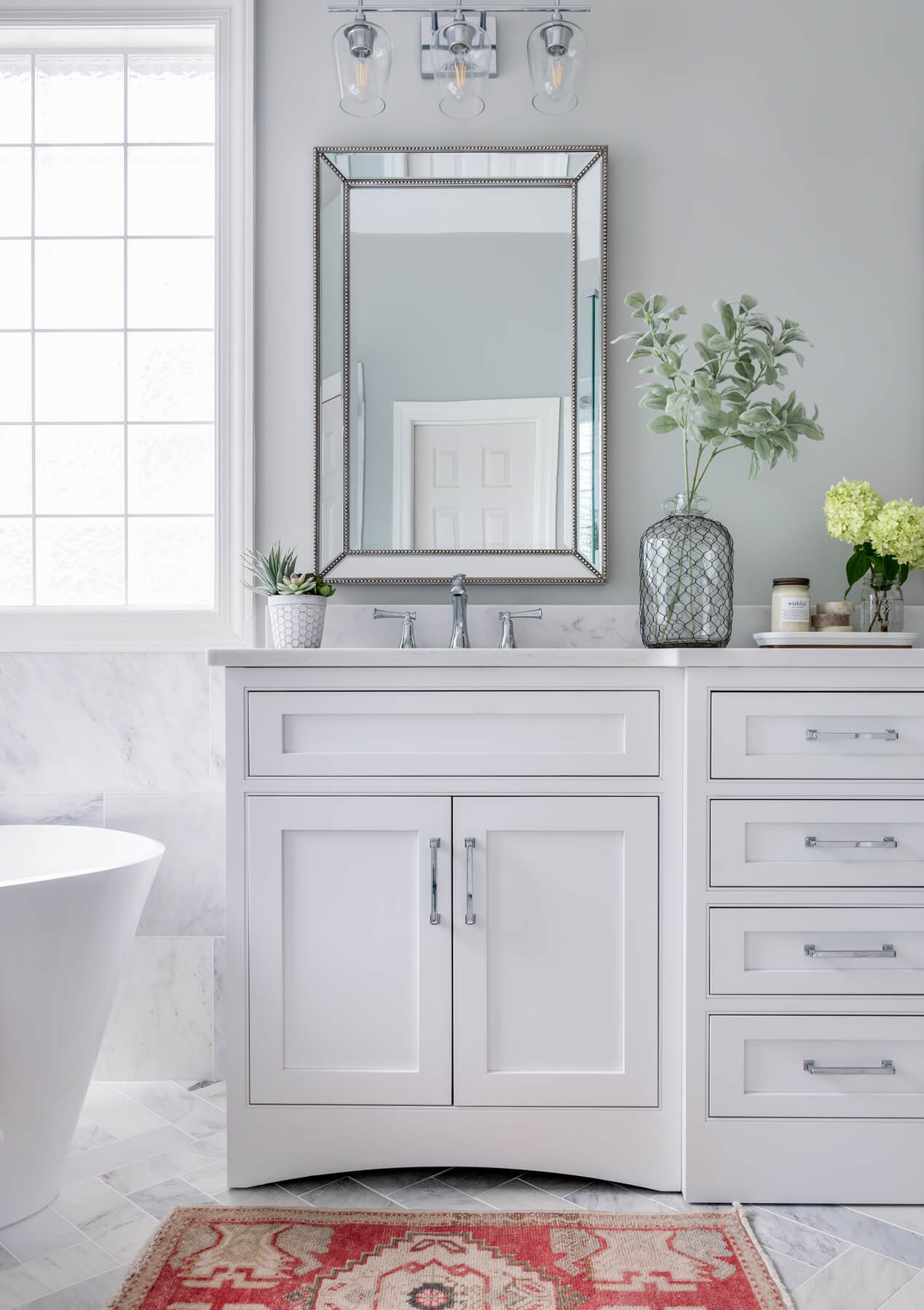 Custom white vanities in a marble bathroom with vallance legs