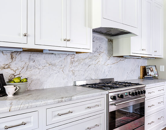 The marble continues up from the countertop into the backsplash, which is a focal point of the space.