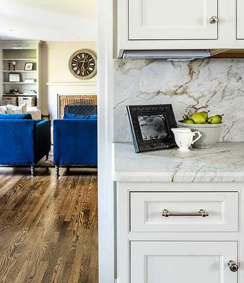 A detail of the marble countertop and slab used as the backsplash, set against the backdrop of the custom cabinets.