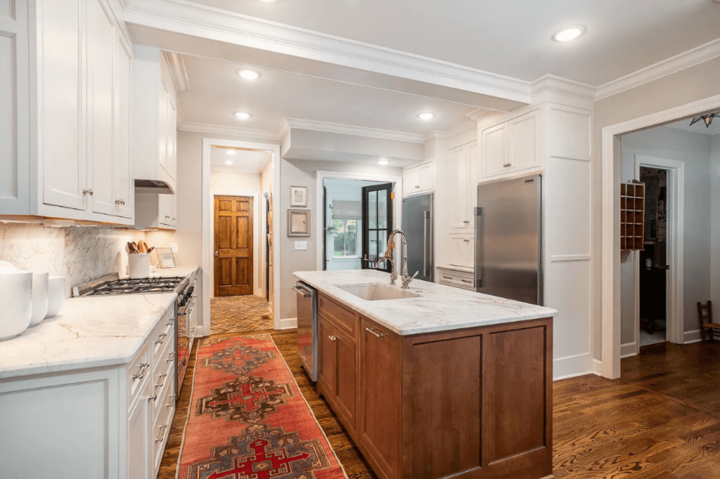 Timeless white kitchen with marble countertops and brown island in the middle